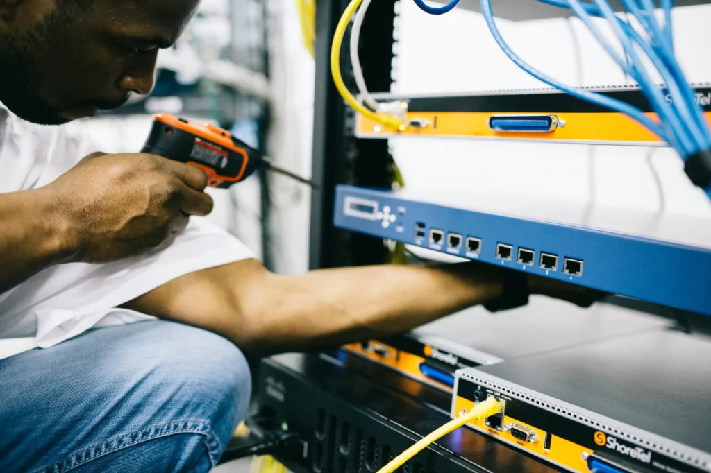 Maintenance réseau sur site – EntreprisePro Technicien informatique effectuant une maintenance sur un rack réseau